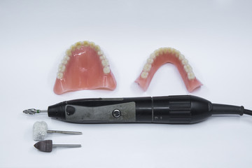 A pair of dentures with a micro motor and some dental grinding tools 