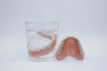 Full Denture in glass of water on white background