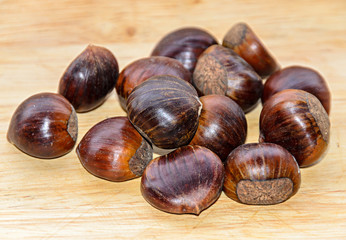 Edible brown chestnuts close up, wooden background