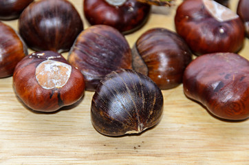 Edible brown chestnuts close up, wooden background