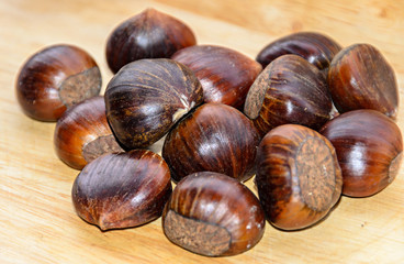 Edible brown chestnuts close up, wooden background