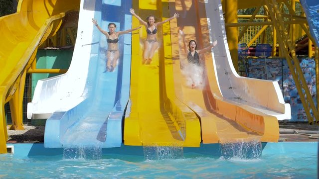 summer fun at water park, brave girls sliding down on waterslides and plunge into pool with Splashing on weekend