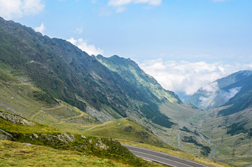 The Transfagarasan road in Fagaras mountains, Carpathians with green grass and rocks, peaks in the clouds
