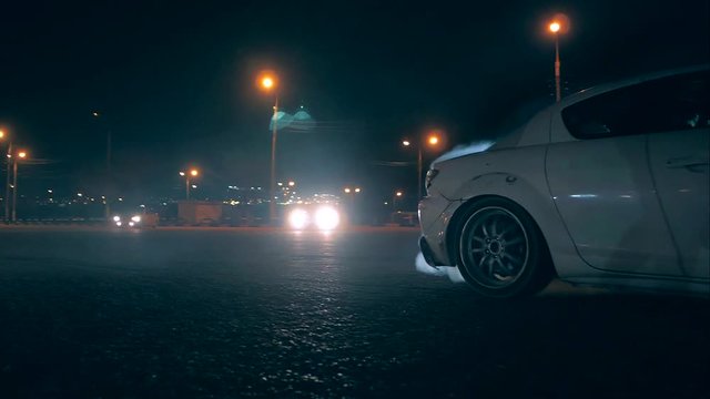 White sports car in drift smoke with tires