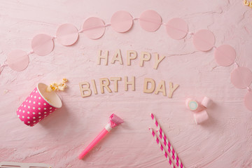 Birthday party background, border of confetti, sweets, lollipops and gift on pink surface, copy space, top view