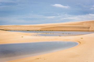 The colorful vast desert landscape of tall, white sand dunes and seasonal rainwater lagoons at the Lençóis Maranhenses National Park, Brasil