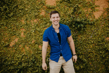 Attractive Male Model in Blue Collared Shirt in front of Orange Textured Vine Wall