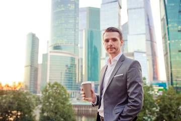 Businessman looking on copy space while standing against glass skyscraper