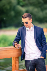 Man is reading text message on mobile phone while walking in the park