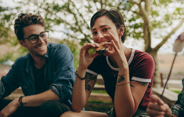 Fototapeta premium Woman on a holiday eating biscuit sandwich sitting outdoors