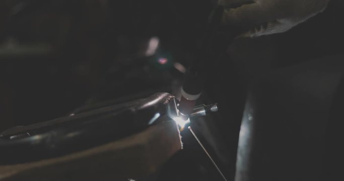 Automaster weld the frame of a custom motorcycle in the garage. Sparks welding machine. Protective face mask. 4k video