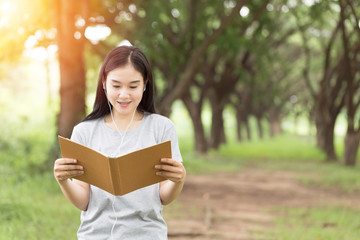 Beautiful attractive Asian young woman smile and reading book to learn and relax with nature in garden feeling so comfortable,Education learning Concept