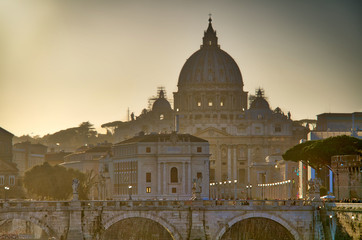 View of the Vatican over the River Tiber with the sun setting behind St. Peter’s Basilica.