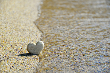 Fototapeta na wymiar Heart stone in the sand, holiday background
