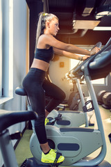 Fototapeta na wymiar Woman Doing Cardio Exercises on a Stationary Bike at the Gym