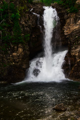 Fototapeta na wymiar Running Eagle Falls in Glacier Nation Park. Running Eagle Falls is named after a female warrior of the Amskapi-Pikuni Native American people. This is a double water fall with both falls flowing in t