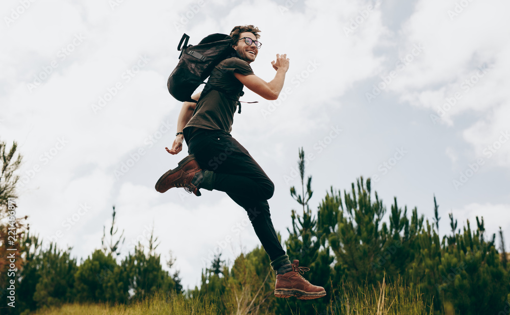 Wall mural happy man jumping during his walk in the forest