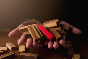 business man try to build wood block on wooden table and black background business organization startup concept