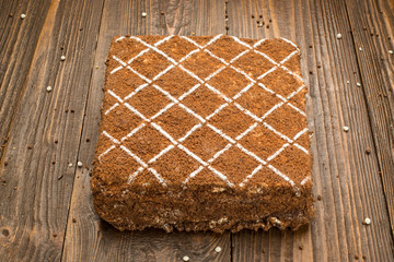 Dark chocolate vegan cake with candies and nuts on wooden background
