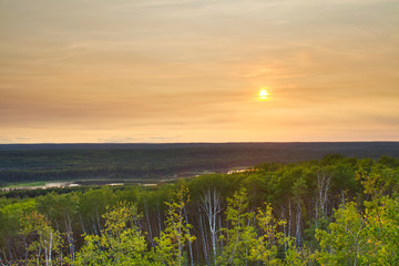 Naklejka na ściany i meble The sun setting over the forest of Prince Albert National Park.
