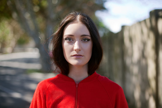 Female model in red top with dappled light and tree in the background