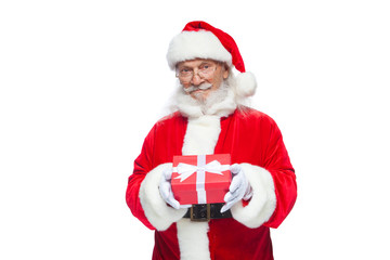 Christmas. Smiling Santa Claus in white gloves is holding a gift red box with a bow. Pointing at the gift. Isolated on white background.