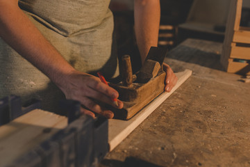 a man  an apron polishes the Board in a carpentry workshop