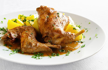stewed in white wine with spices rabbit legs with gravy and potato sprinkled with parsley