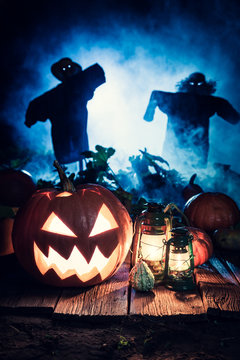 Scary Halloween pumpkin with scarecrows and blue mist