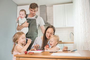 family smiling happily sitting together in the kitchen working and doing their children's homework. Family spending time together in kitchen