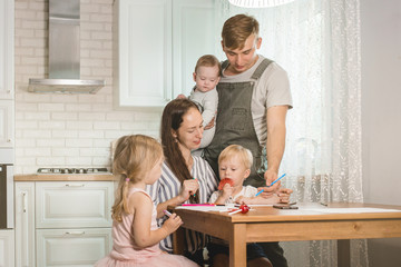 family smiling happily sitting together in the kitchen working and doing their children's homework. Family spending time together in kitchen