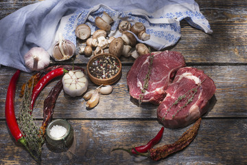 Fresh natural beef steaks for grill with species, salt, pepper on a wooden background.