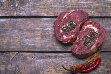 Plakat Beef steak from raw meat for roasting, salt, pepper on a wooden background.