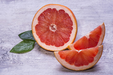 Half of fresh citrus fruit grapefruit with slices on a gray wooden table.