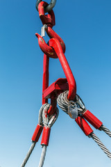 hook of a crane lifts a load on the background of blue sky