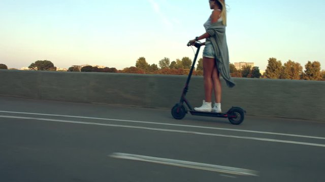 Attractive woman ride on the electric kick scooter