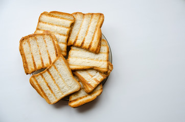 Bread baked on the grill lies ona plate on a white background. Top view.
