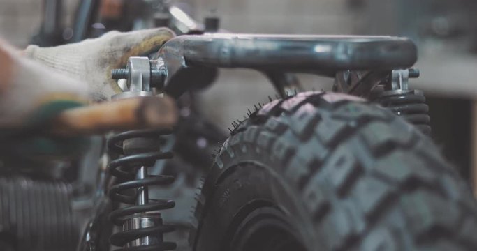 Auto mechanic assembles custom motorcycle in his workshop. Guy create an exclusive motobike cafe racer in the garage.