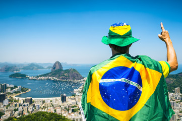 Patriotic Brazilian fan wrapped in flag holding up hand with 'number 1' signal at Sugarloaf...