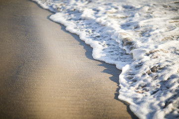 Abstract detail of foamy wave crashing up on a sandy beach