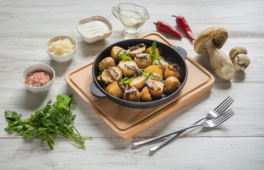 Country potatoes with fried mushrooms on a cast iron pan.
