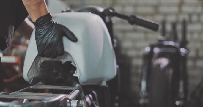Auto mechanic assembles custom motorcycle in his workshop. Guy create an exclusive motobike cafe racer in the garage.