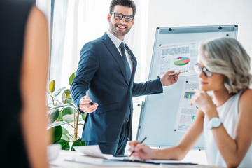 happy businessman pointing on flipchart during presentation in office