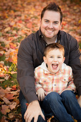 Happy Father and Son Sitting in Autumn Park