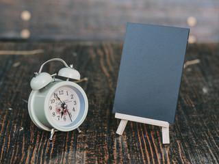 twinbell clock, cup of coffee, and mini blackboard on the wooden table. Image is concept of evening time