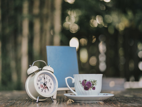 twinbell clock, cup of coffee, and mini blackboard on the wooden table. Image is concept of evening time