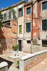 Venice court with ancient water well, buildings and houses facades in a sunny day in Italy