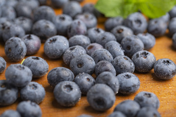 Juicy and fresh blueberries with green mint leaves on a wooden table. Blueberries on wooden background.