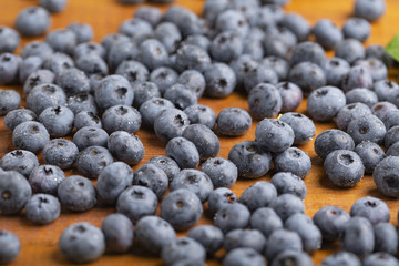 Juicy and fresh blueberries with green mint leaves on a wooden table. Blueberries on wooden background.