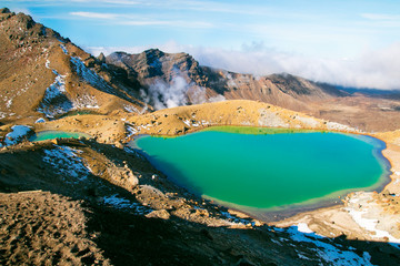 Stunning emerald blue lake in high magnitude of World's Heritage Tongariro National Park, Great Walk, smoking sulphur from the ground of active volcanic rocks, New Zealand mountains landscape